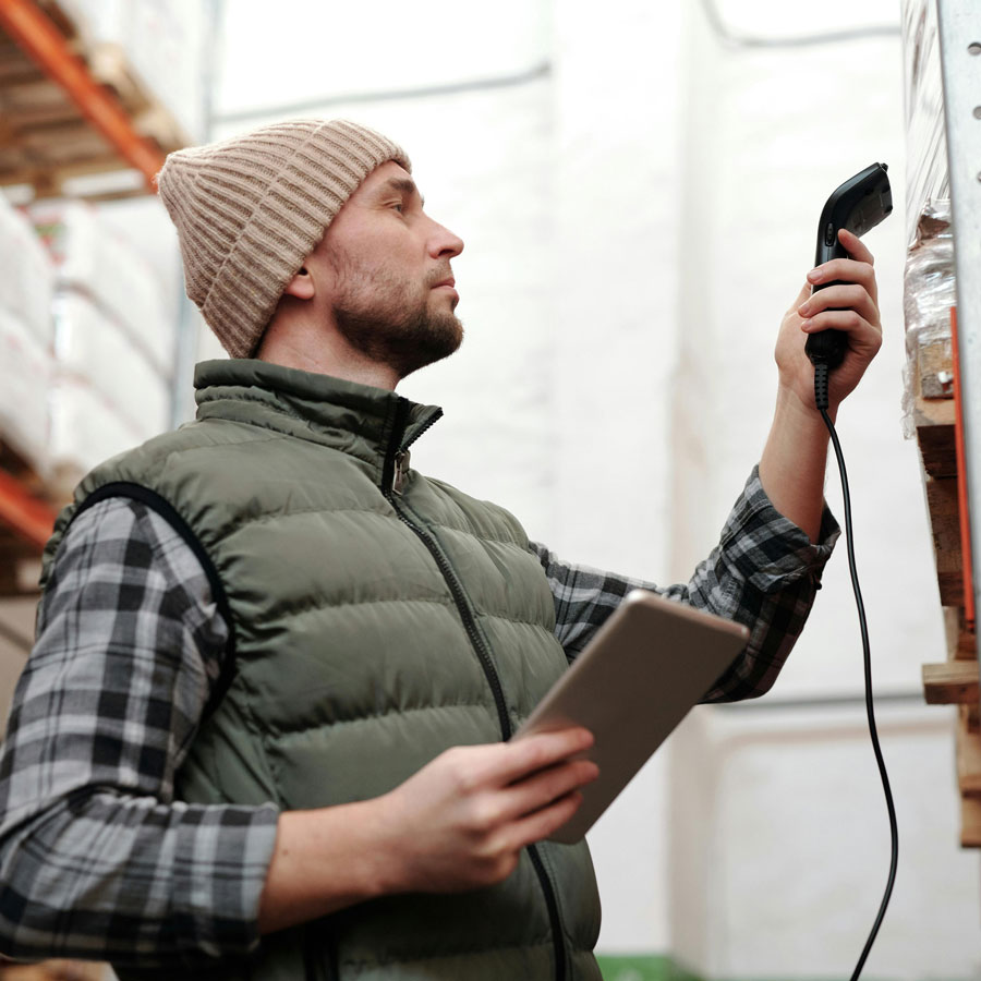 Scanning Bought Surplus Man in a warehouse scanning products with a barcode reader and holding a tablet.