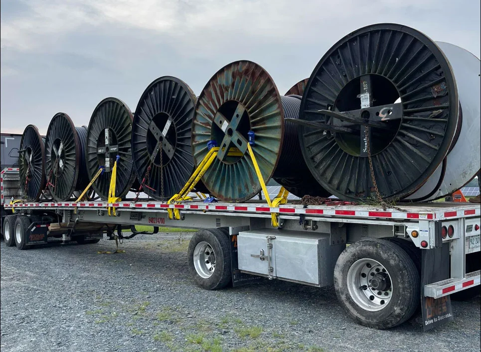 A flatbed truck loaded with large electrical wire spools, ready for transport from unitedindustriesva.com.