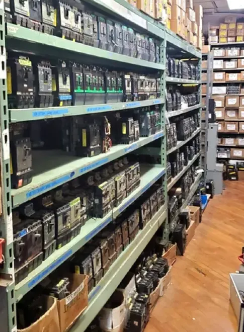Our Surplus Electrical Equipment Inventory Industrial shelves packed with various circuit breakers and electrical components, showcasing United Industries' extensive inventory for electrical needs.