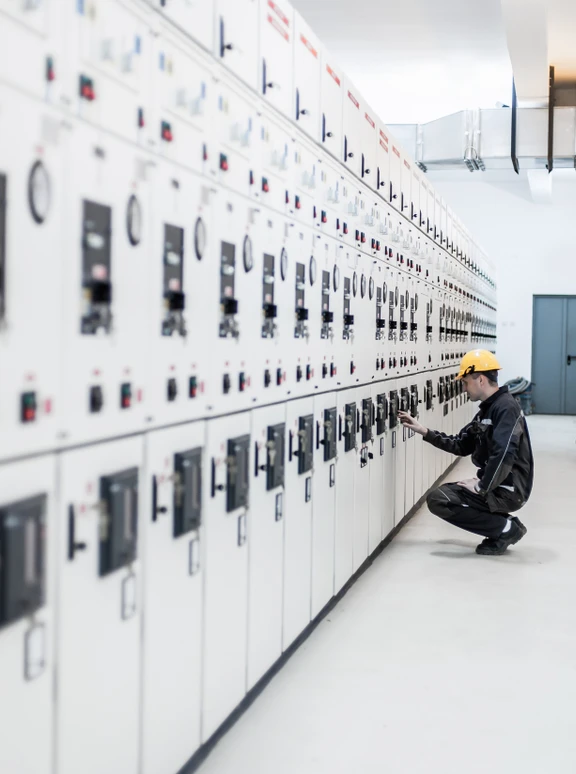 Electrical Engineer Inspecting Industrial Switchgear Panel Engineer in hard hat checking industrial switchgear control panel in a clean facility.