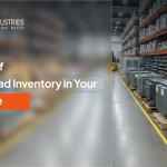 Large industrial transformers on wooden pallets lined up in a warehouse aisle next to tall storage racks.